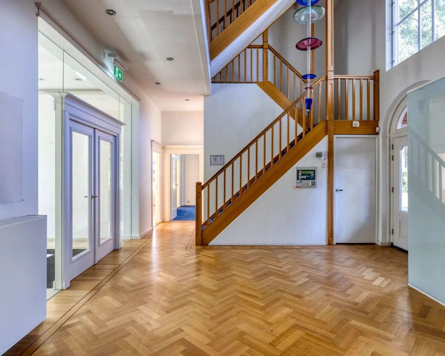 Entreehal van een kantoorruimte aan de Utrechtseweg 47 in Hilversum met houten trap en visgraat parketvloer.