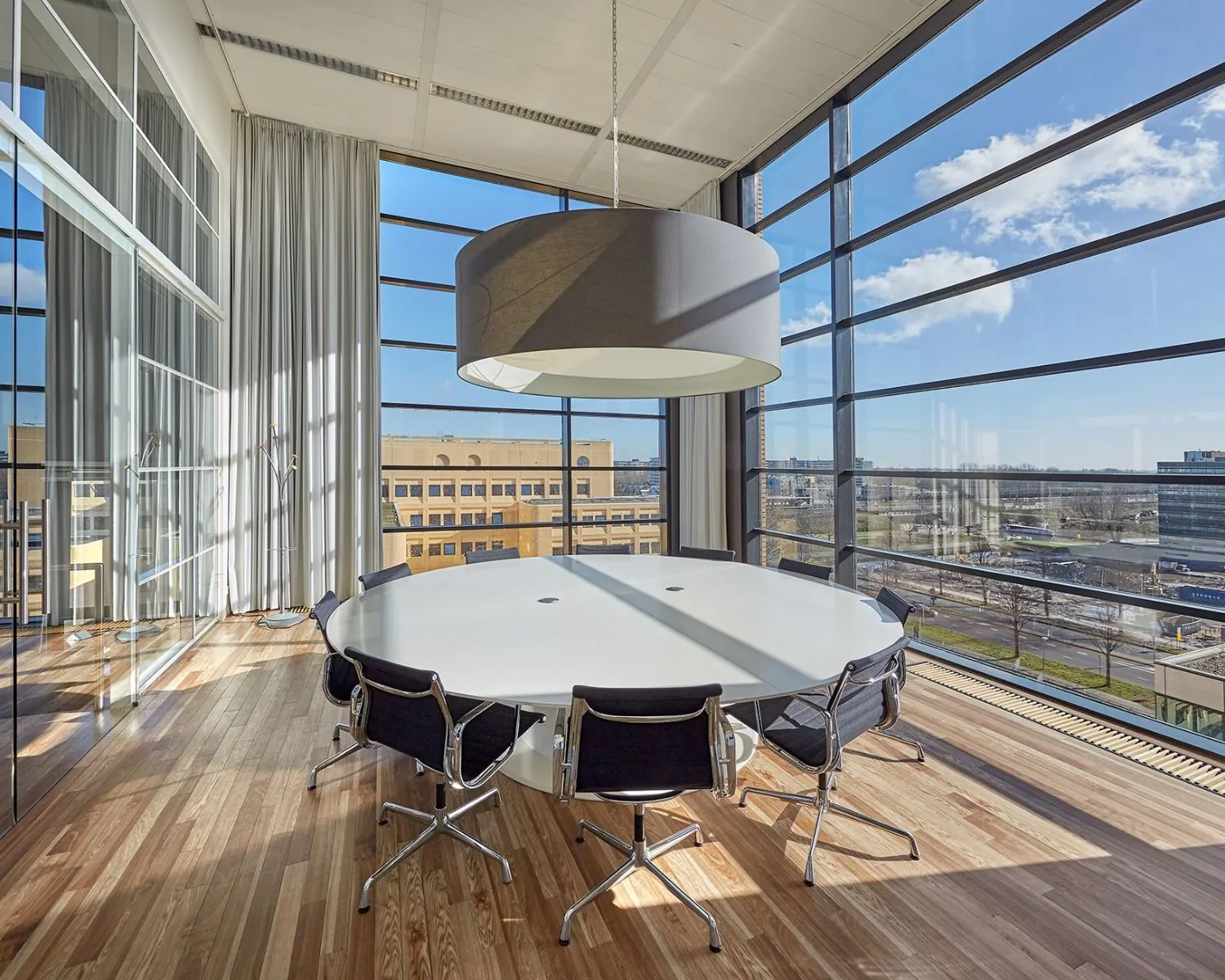 Moderne vergaderruimte met grote ramen en een rond wit tafelblad in kantoor Hogehilweg 24.