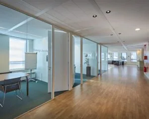 Moderne kantoorruimte aan de Hogehilweg 24-3 met glazen vergaderruimtes en een ruime, lichte gang.