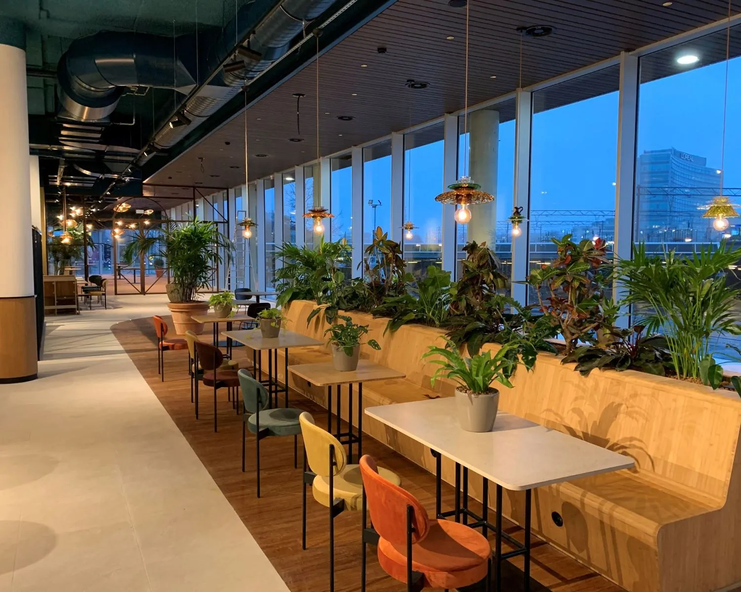 Moderne kantoorruimte te huur aan het Mercuriusplein in Hoofddorp met kleurrijke zitplekken, veel planten en grote ramen met uitzicht.