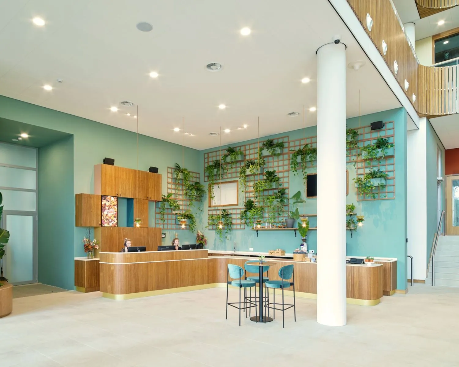 Moderne en lichte entree met receptiebalie en groene wand in een kantoorpand aan het Mercuriusplein in Hoofddorp.