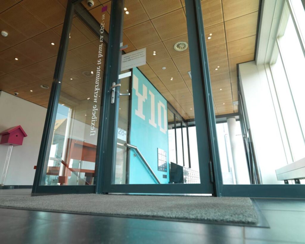 Entree van een moderne kantoorruimte aan de IJburglaan met glazen deuren en een opvallende blauwe muur met het nummer 610.