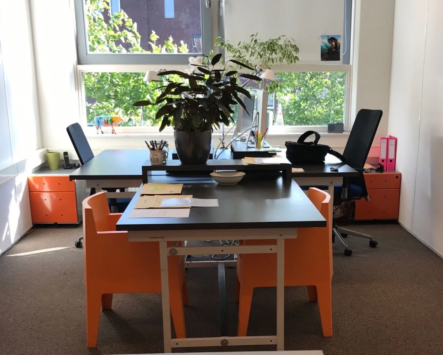 Moderne kantoorruimte aan de IJburglaan met twee werkplekken, veel daglicht en oranje accenten.