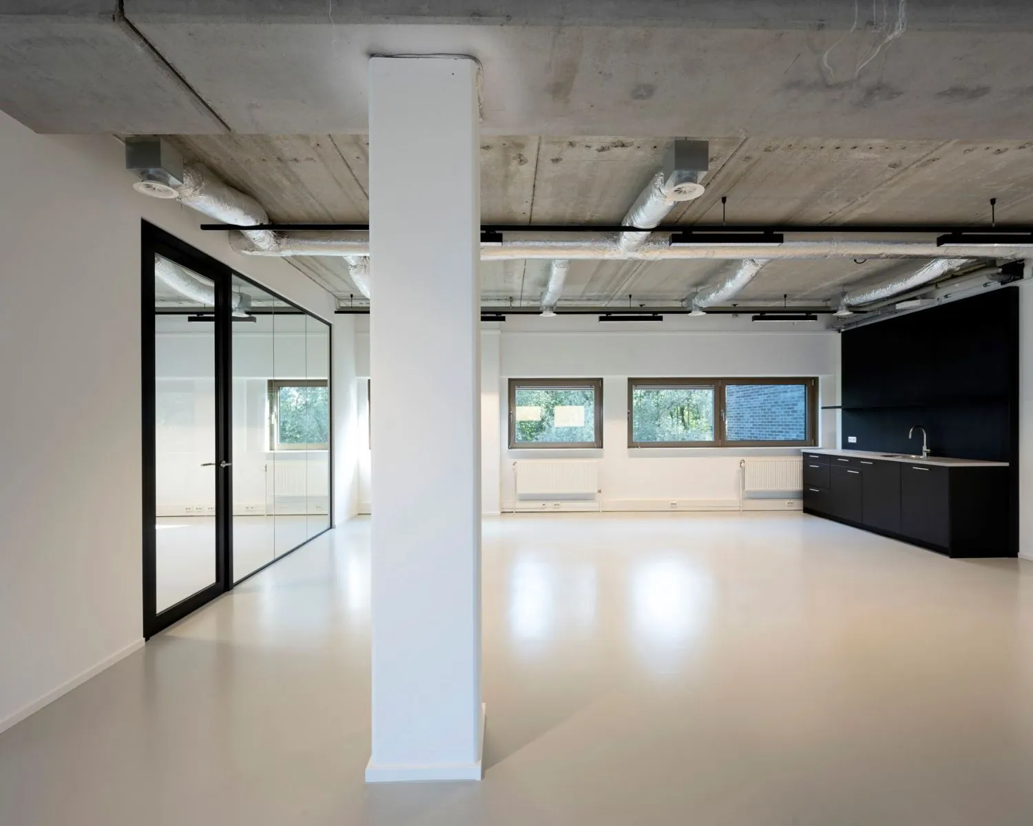 Moderne, lichte kantoorruimte aan de Joop Geesinkweg met grote ramen, glazen scheidingswand en een kitchenette.