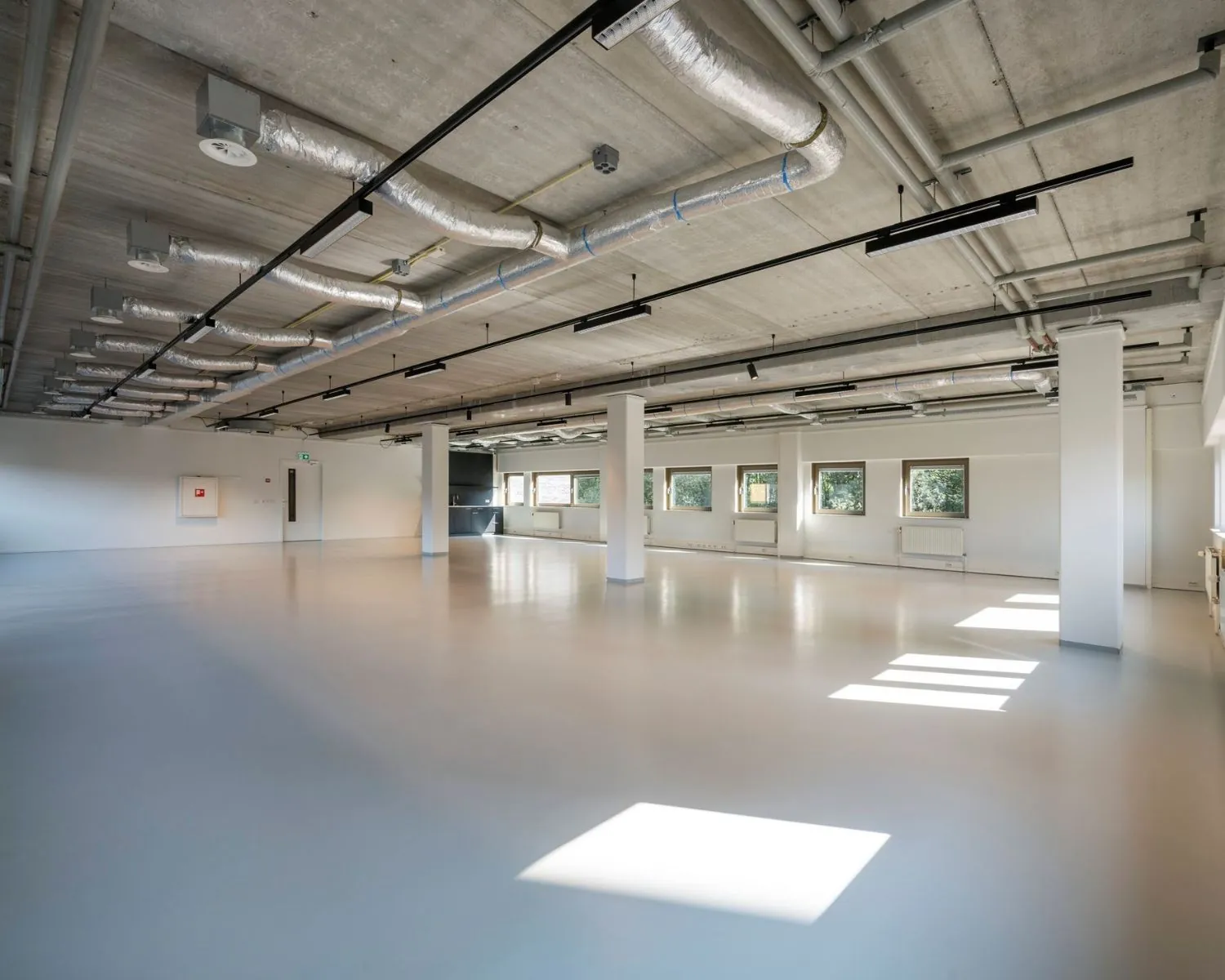 Ruime, lichte kantoorruimte te huur aan de Joop Geesinkweg met industriële afwerking en grote ramen.