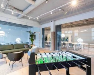 Moderne kantoorruimte aan de Joop Geesinkweg met glazen vergaderruimtes, loungehoek en een tafelvoetbaltafel.