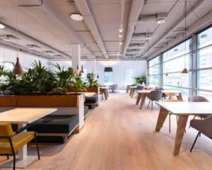 Moderne en lichte kantoorruimte met grote ramen, houten vloeren en diverse zitplekken aan de Joop Geesinkweg.