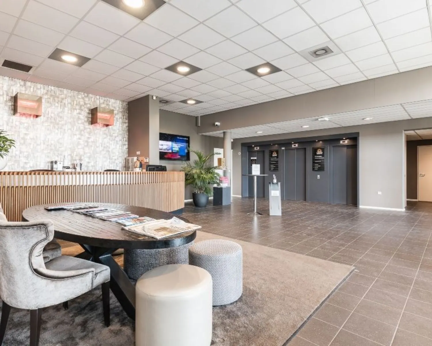 Moderne en ruime ontvangsthal met zitgelegenheid, receptiebalie en liften in een kantoorpand aan de Joop Geesinkweg.