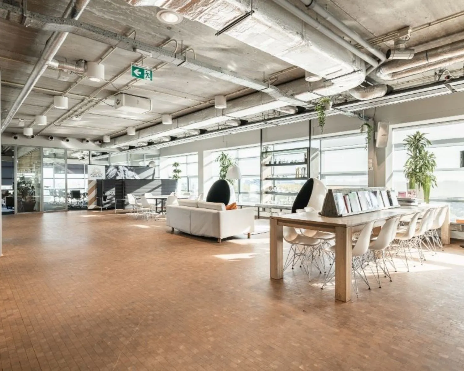 Moderne kantoorruimte met industriële look, grote ramen en een open lounge- en werkruimte aan de Joop Geesinkweg.