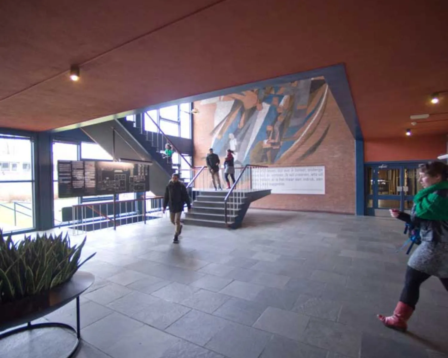 Ingangshal met trap en muurkunst in een kantoorruimte aan de Krelis Louwenstraat.
