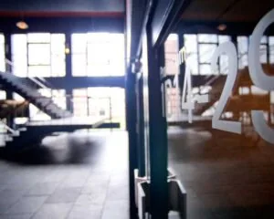 Moderne entreehal van een kantoorruimte aan de Krelis Louwenstraat met glazen wand en zicht op een industriële trap.