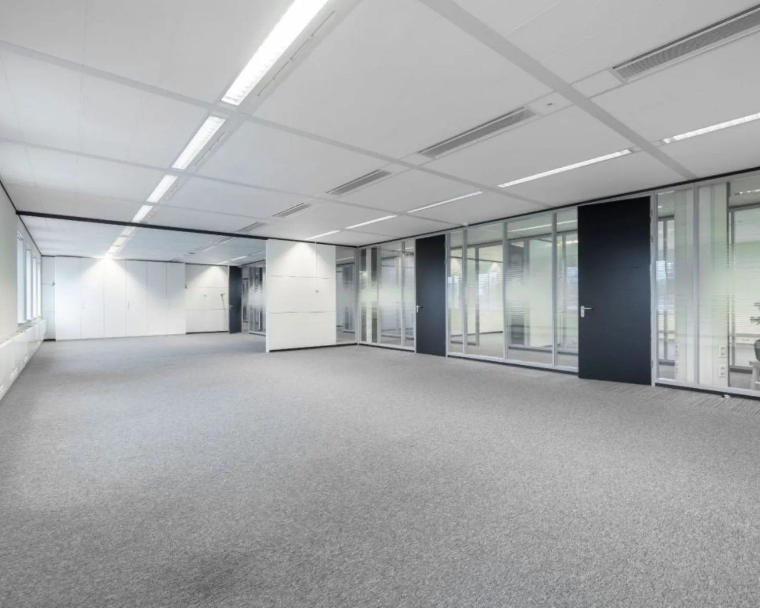 Moderne, lege kantoorruimte met tapijtvloer en glazen scheidingswanden aan de Meander 901 in Arnhem.