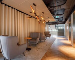 Moderne wachtruimte in een kantoorruimte aan de Meander 901 in Arnhem, met comfortabele stoelen, houten vloer en sfeerverlichting.