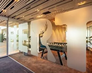 Moderne kantoorruimte in Arnhem met glazen wand, opdruk en tafelvoetbaltafel in een sfeervol ingerichte lounge.