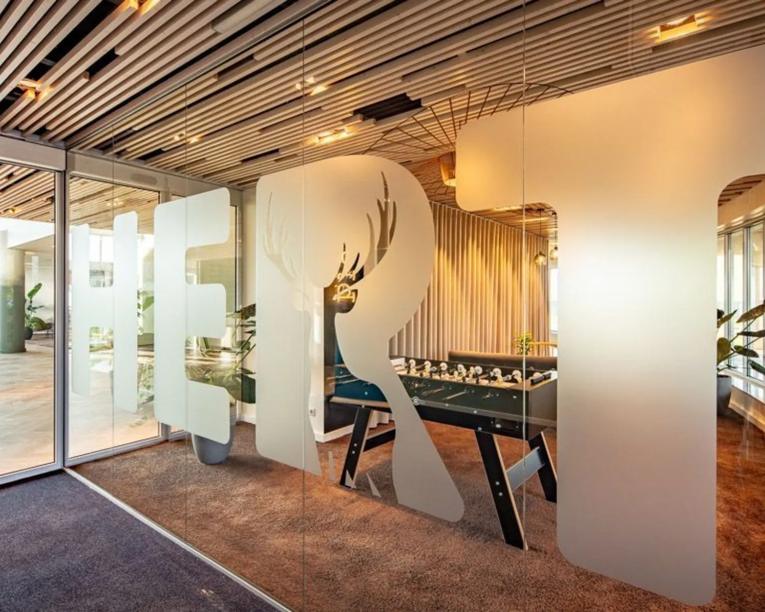 Moderne kantoorruimte in Arnhem met glazen wand, opdruk en tafelvoetbaltafel in een sfeervol ingerichte lounge.