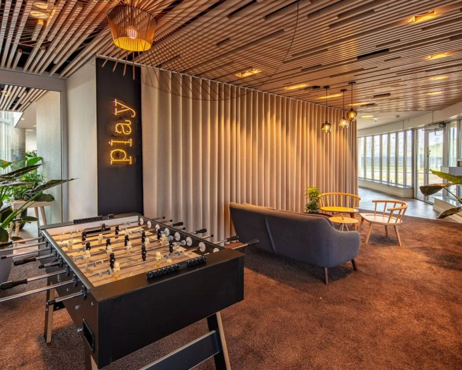 Moderne lounge- en speelruimte in kantoor aan de Meander 901 in Arnhem met tafelvoetbaltafel, zitgedeelte en sfeervolle verlichting.