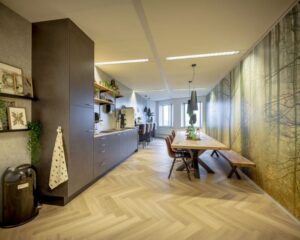 Moderne kantoorruimte in Arnhem met open keuken, lange houten vergadertafel en natuurwanddecoratie.