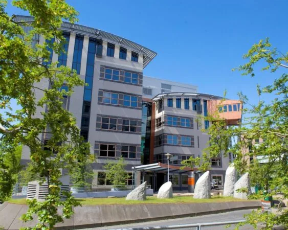 Moderne kantoorruimte in gebouw Olympia met opvallende architectuur en groenvoorziening aan de voorkant.