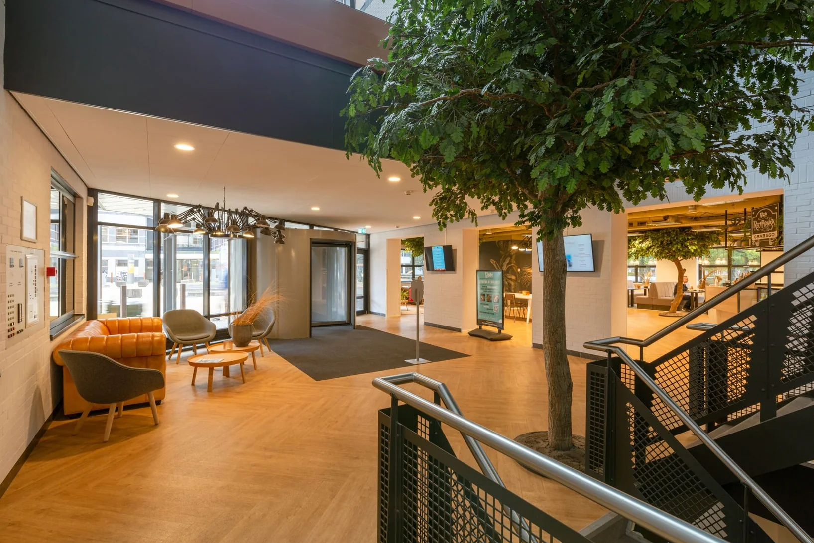 Moderne en open kantoorruimte met zithoek, grote binnentuinboom en ontvangstruimte in Olympia 1-4.