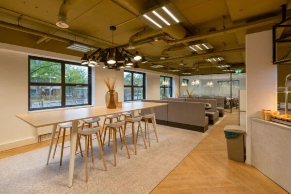 Moderne kantoorruimte te huur aan Olympia 1-5 met hoge tafels, comfortabele zitplekken en stijlvolle verlichting.