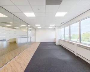 Moderne kantoorruimte te huur aan de Overschiestraat 61 met grote ramen, glazen wanden en een combinatie van tapijt en houtlook vloer.