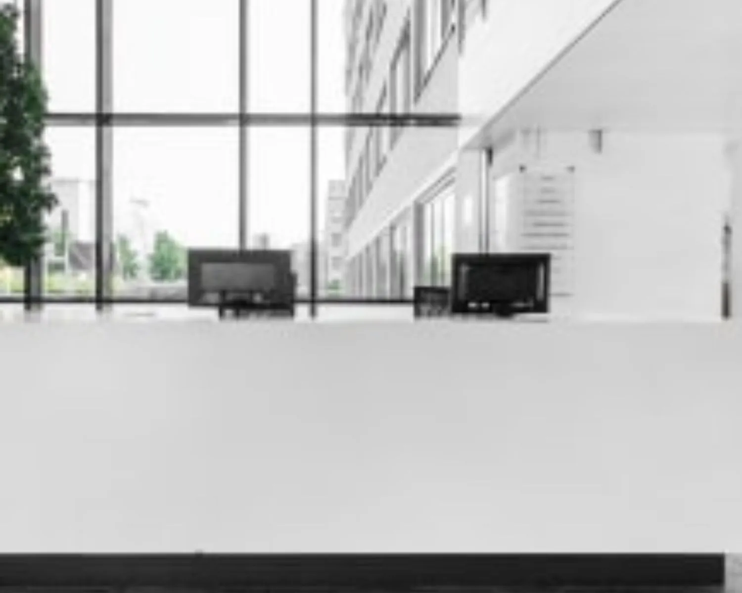 Moderne, lichte entree met receptiebalie en computers in een kantoorpand aan de Paterswoldseweg.