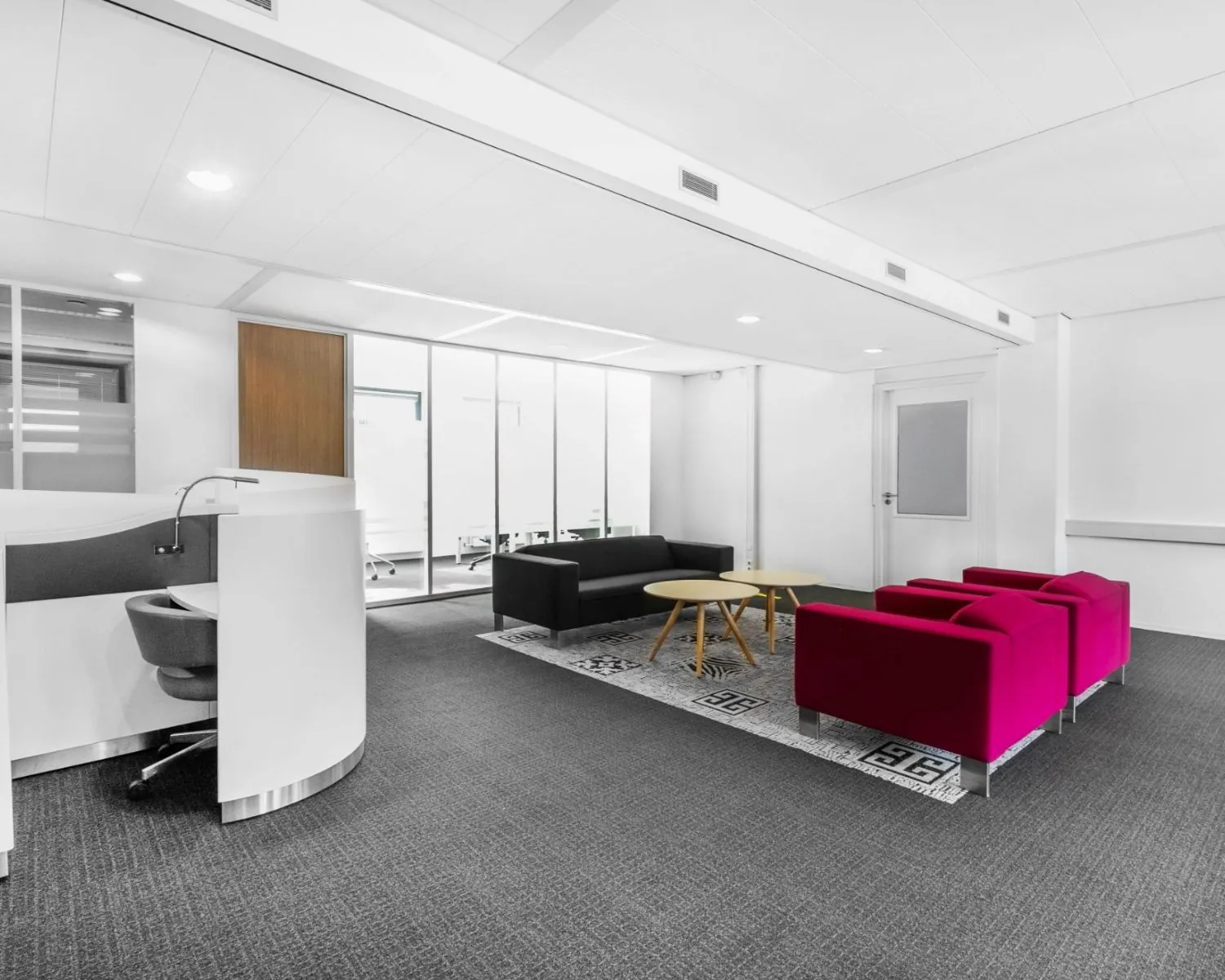 Moderne kantoorruimte aan de Paterswoldseweg met een wachtruimte met kleurrijke fauteuils, zwarte banken en een werkplek.