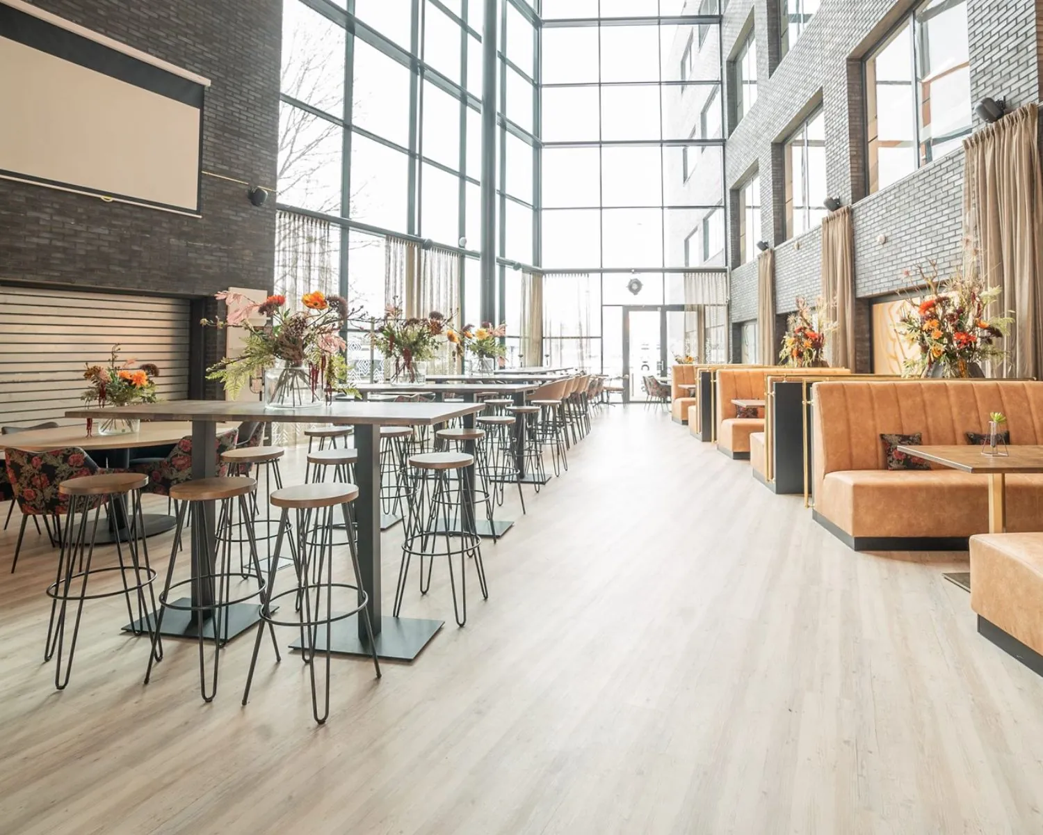 Modern ingerichte kantoorruimte met hoge ramen, zithoeken en hoge tafels in het gebouw aan de Professor W.H. Keesomlaan 12.