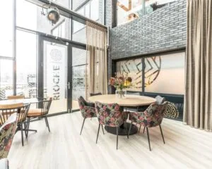 Moderne en lichte kantoorruimte aan de Professor W.H. Keesomlaan met ronde tafel, bloemen en stijlvolle stoelen in een gemeenschappelijke zithoek.