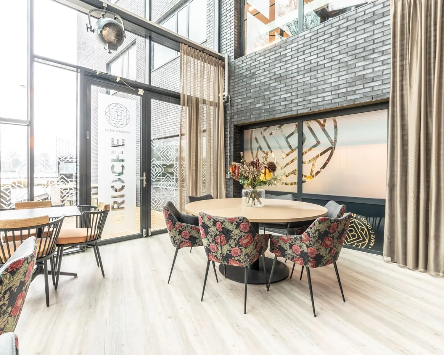 Moderne en lichte kantoorruimte aan de Professor W.H. Keesomlaan met ronde tafel, bloemen en stijlvolle stoelen in een gemeenschappelijke zithoek.