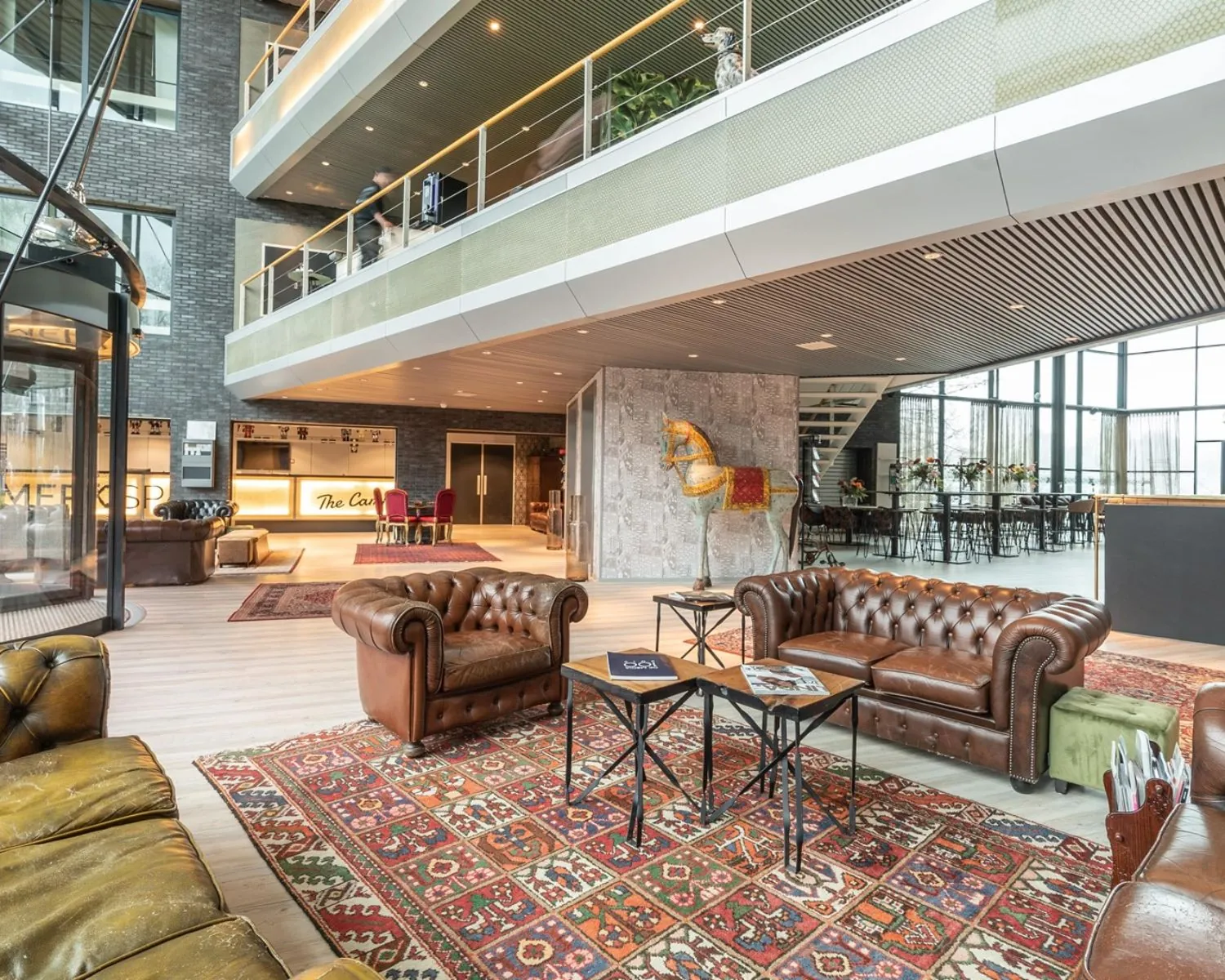 Moderne en stijlvolle kantoorlounge op Professor W.H. Keesomlaan 12 met leren banken, vintage vloerkleden en een opvallend houten paard.
