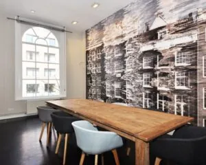 Stijlvolle vergaderruimte met houten tafel, moderne stoelen en een muurdecoratie van Amsterdamse grachtenpanden in kantoorruimte aan Rapenburg 173.