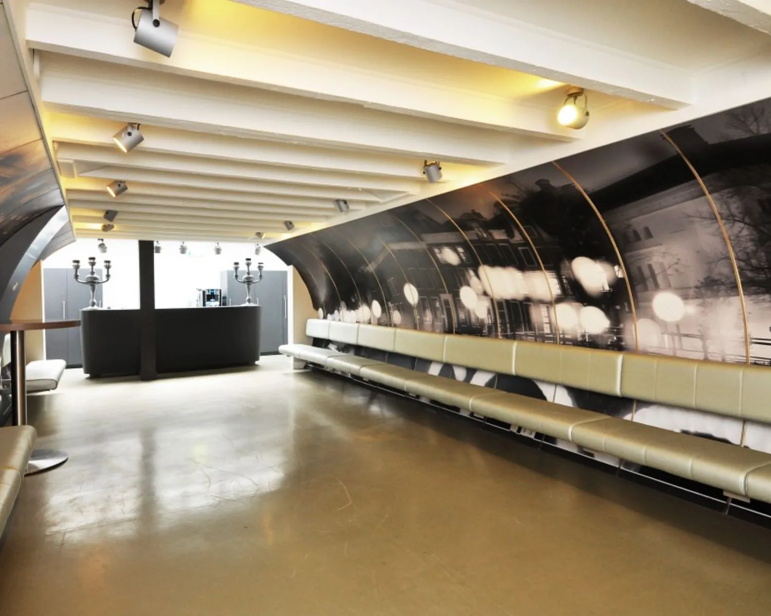 Moderne kantoorruimte aan de Rapenburgerstraat met lange zitbank, fotoprint op de muur en een koffiebar achterin.