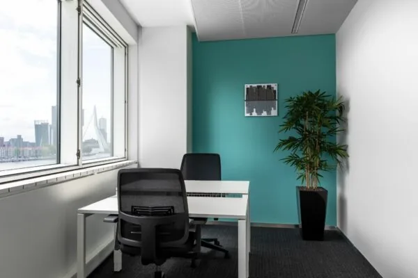 Moderne kantoorruimte met twee bureaus, uitzicht op de Erasmusbrug en een turquoise achterwand, gelegen aan Boompjes 40 in Rotterdam.