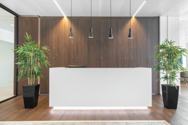 Moderne receptiebalie met witte balie, houten wand, hanglampen en planten in kantoorruimte aan de Boompjes 40 in Rotterdam.