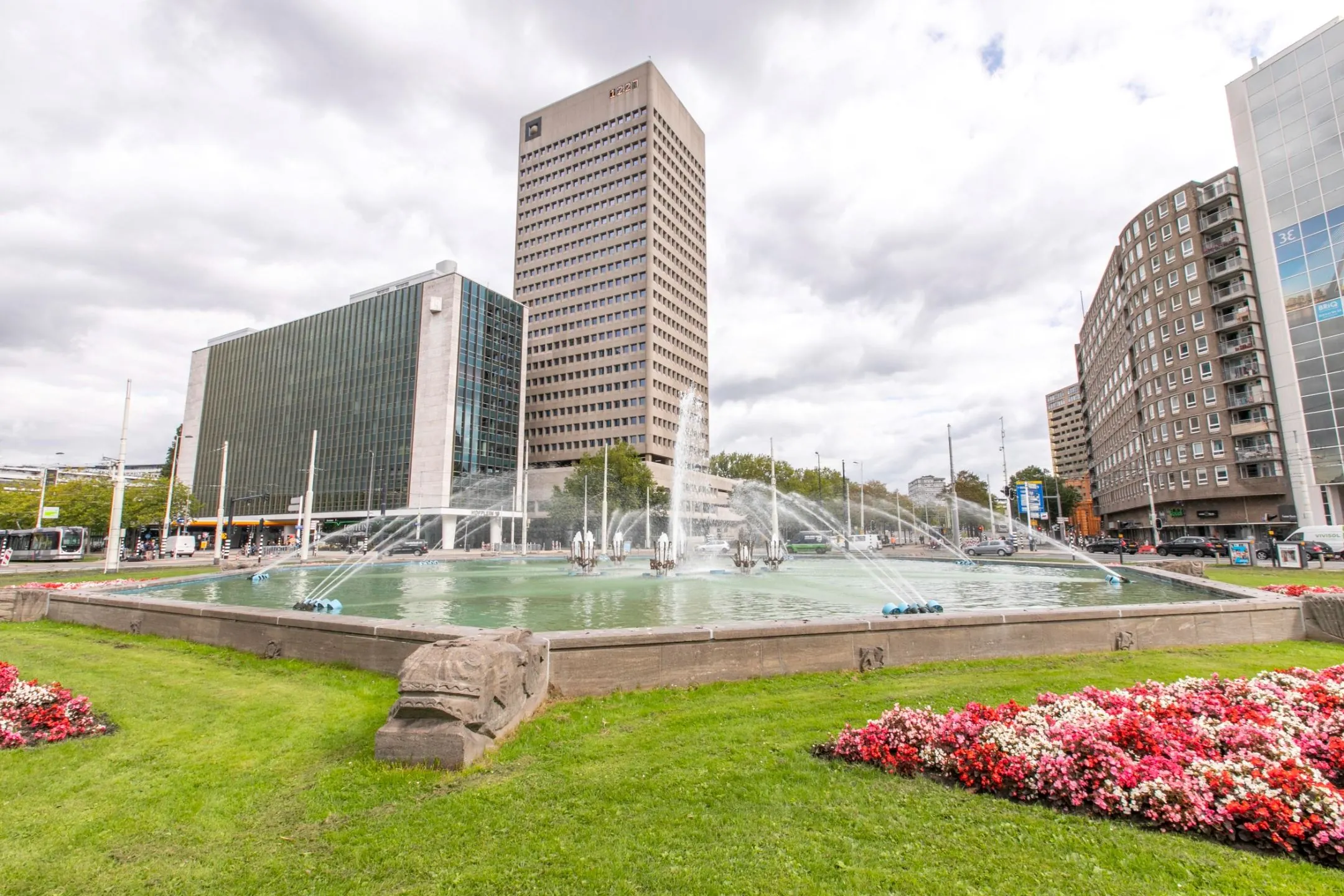 Kantoorgebouw aan het Hofplein 20 in Rotterdam met fontein en omliggende bloemenperk op de voorgrond.