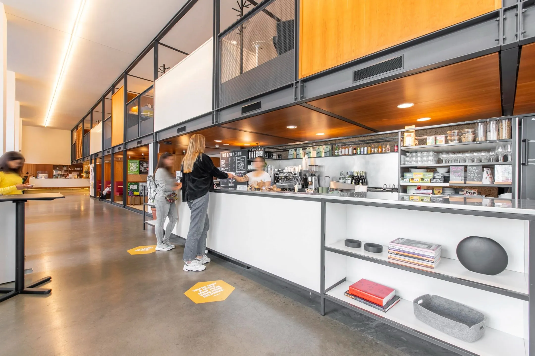 Moderne koffiebar in kantoorruimte aan Hofplein 20 in Rotterdam met mensen die bestellen.