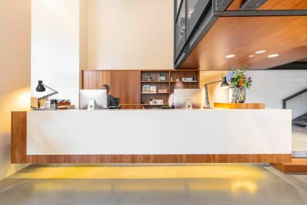 Moderne receptiebalie met twee medewerkers in een kantoorruimte aan Hofplein 20 in Rotterdam.