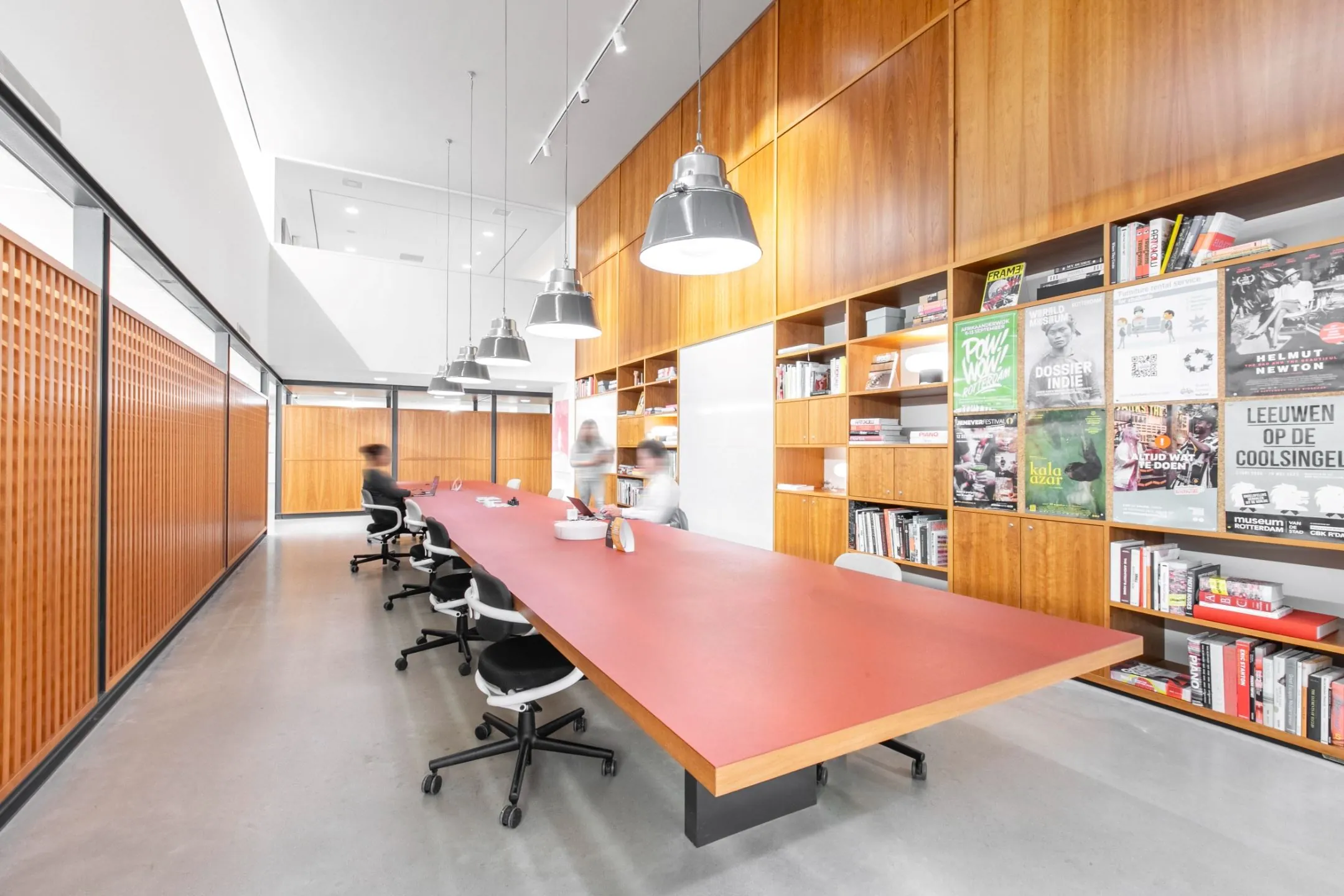 Moderne vergaderruimte met lange tafel, designstoelen en houten kastenwand in kantoor aan Hofplein 20 in Rotterdam.