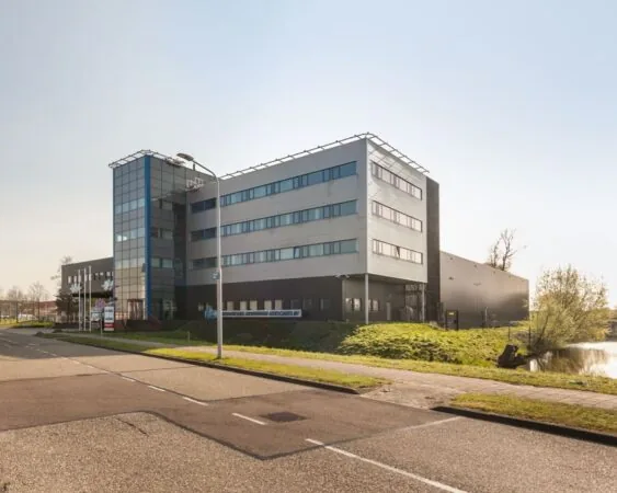 Modern kantoorgebouw aan de Capronilaan 12-20 in Schiphol-Rijk, gelegen naast een waterpartij.