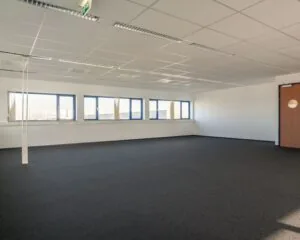 Lege kantoorruimte met systeemplafond en blauw omlijste ramen aan de Capronilaan in Schiphol-Rijk.