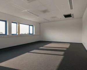 Leegstaand kantoor met grijze vloerbedekking en blauwomrande ramen aan de Capronilaan in Schiphol-Rijk.