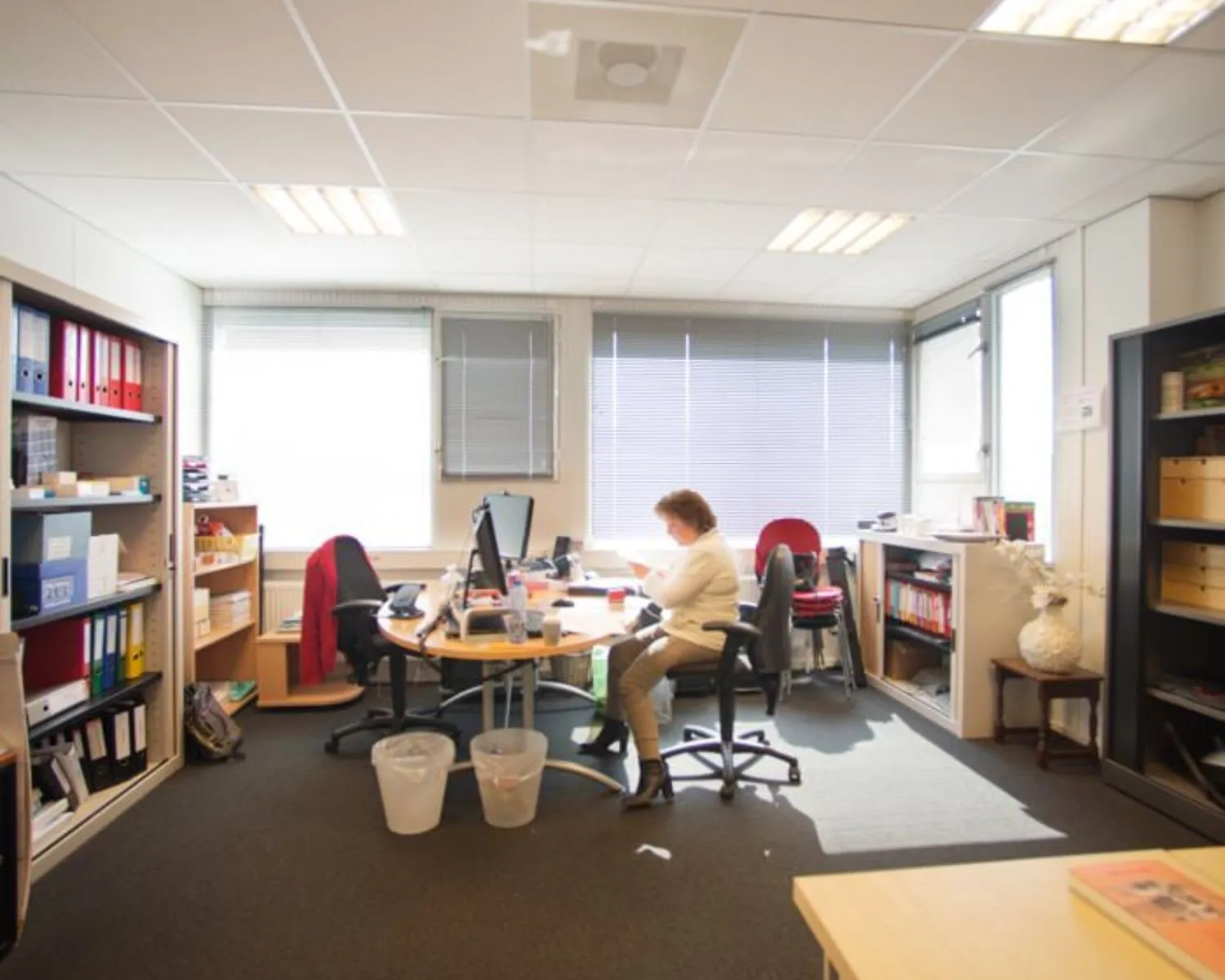 Kantoorruimte aan de Slotermeerlaan 67-3 met bureaus, kasten en een persoon die aan het werk is.