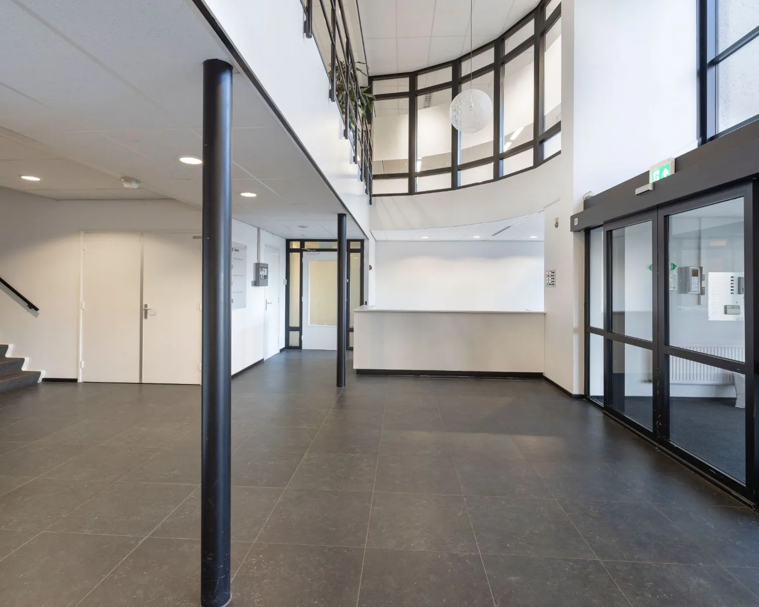 Moderne en lichte entreehal van een kantoorruimte aan de Stephensonweg met balie, trap en glazen buitendeur.