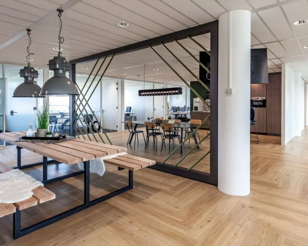 Moderne, open kantoorruimte aan de Tupolevlaan 73 met houten vloeren, glazen vergaderruimtes en een gezamenlijke zit- en eetruimte.