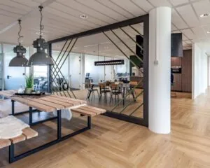 Moderne, open kantoorruimte aan de Tupolevlaan 73 met houten vloeren, glazen vergaderruimtes en een gezamenlijke zit- en eetruimte.