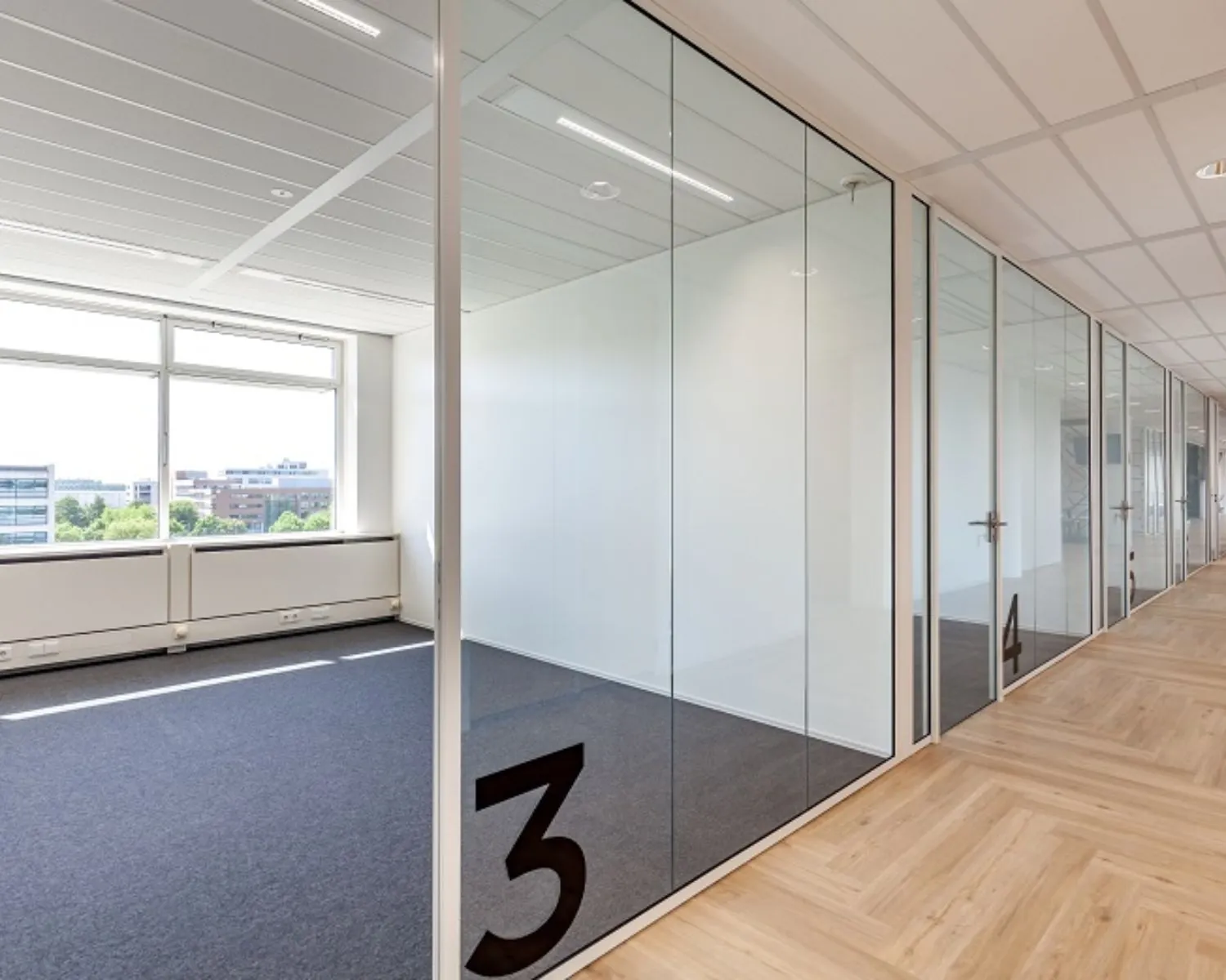 Moderne kantoorruimte met glazen wanden en genummerde kamers aan de Tupolevlaan 73.