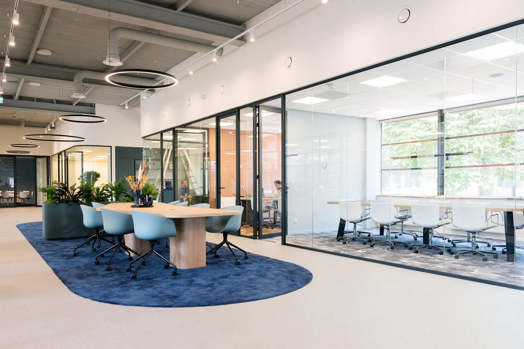 Moderne kantoorruimte met glazen vergaderruimtes en gezamenlijke werktafel aan de Atoomweg 50 in Utrecht.