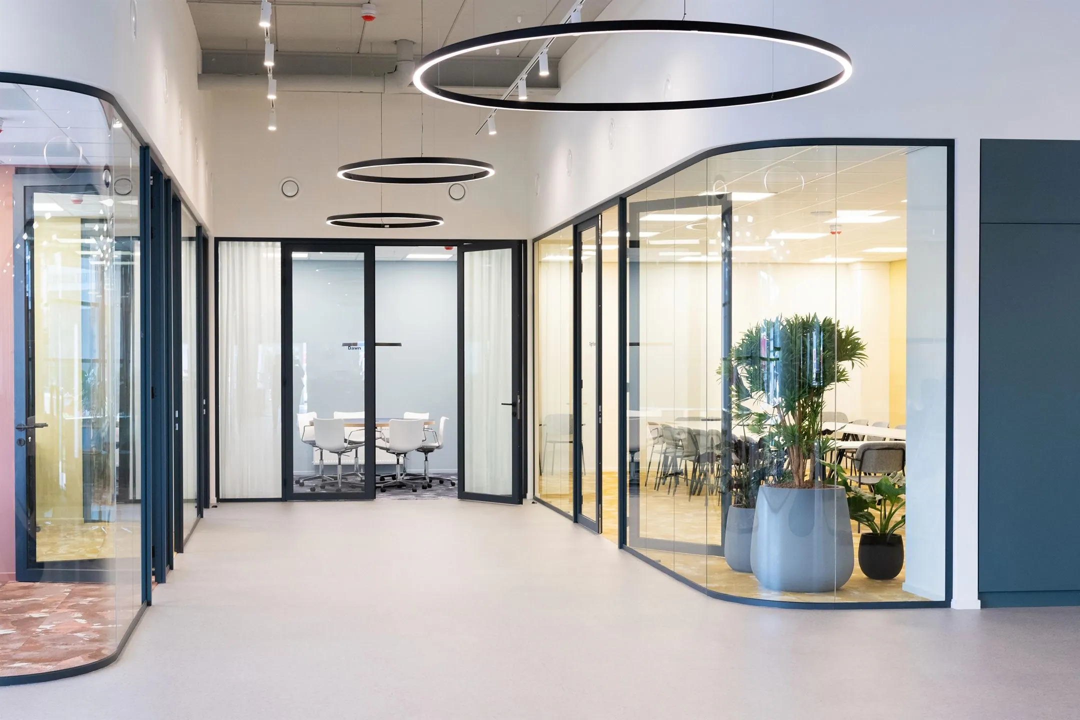 Moderne kantoorruimte in Utrecht aan de Atoomweg 50-12 met glazen vergaderruimtes, minimalistisch interieur en grote planten.