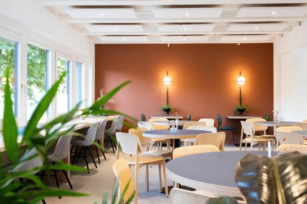 Moderne en lichte kantoorruimte met meerdere zitplekken en een warme oranjebruine accentmuur aan de Atoomweg 50 in Utrecht.